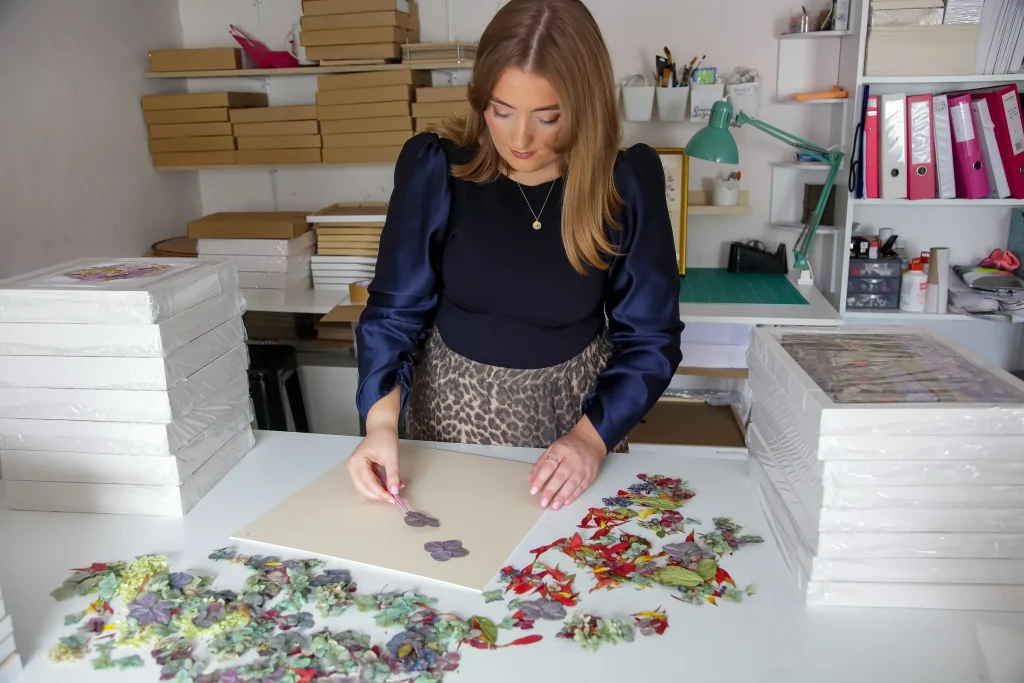 Nell at her studio table arranging pressed petals on a board