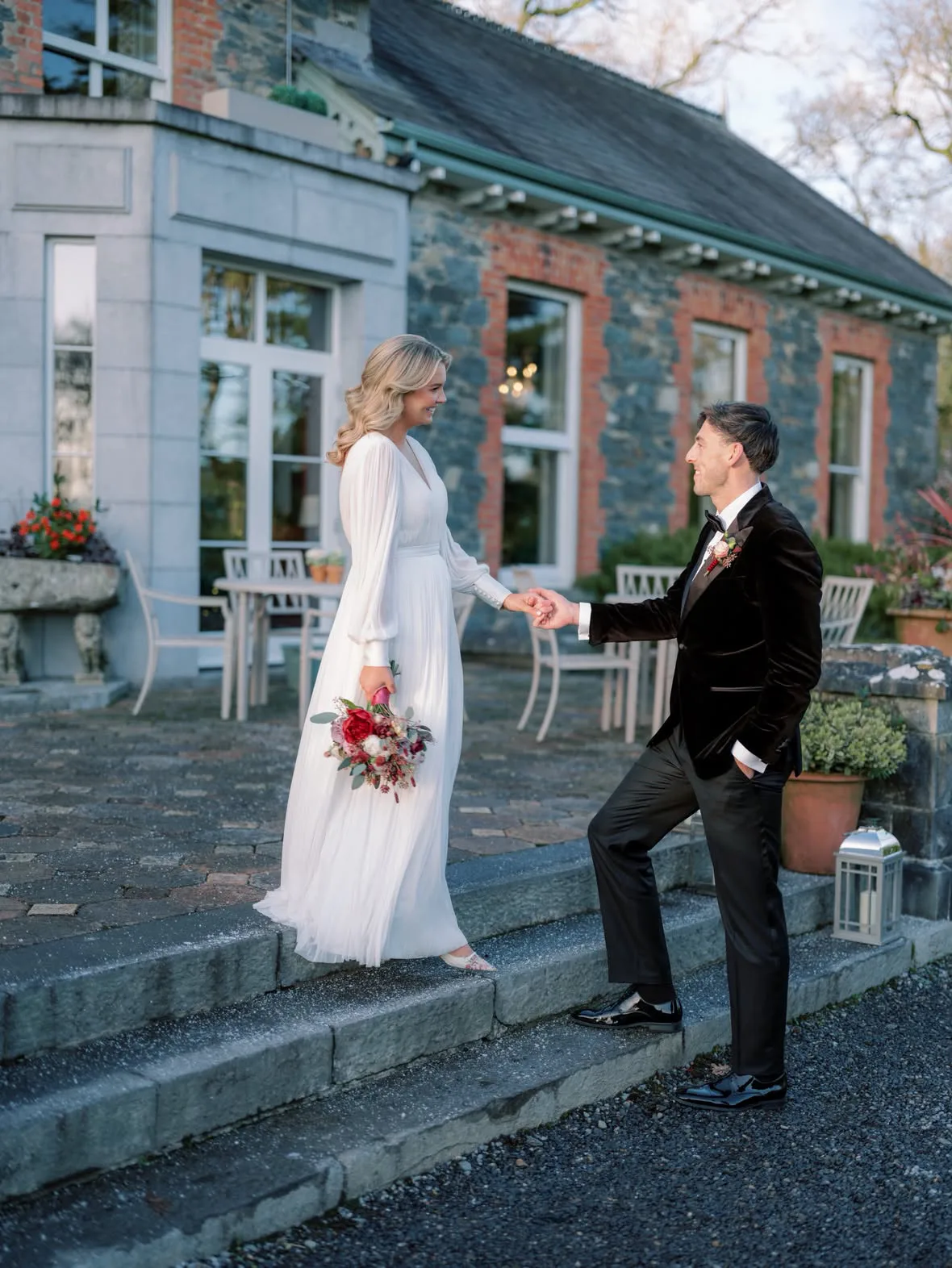 A bride and groom on the steps of their wedding venue