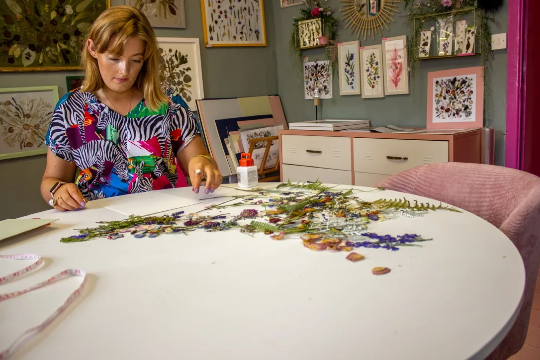 Nell arranging pressed flowers at the studio table